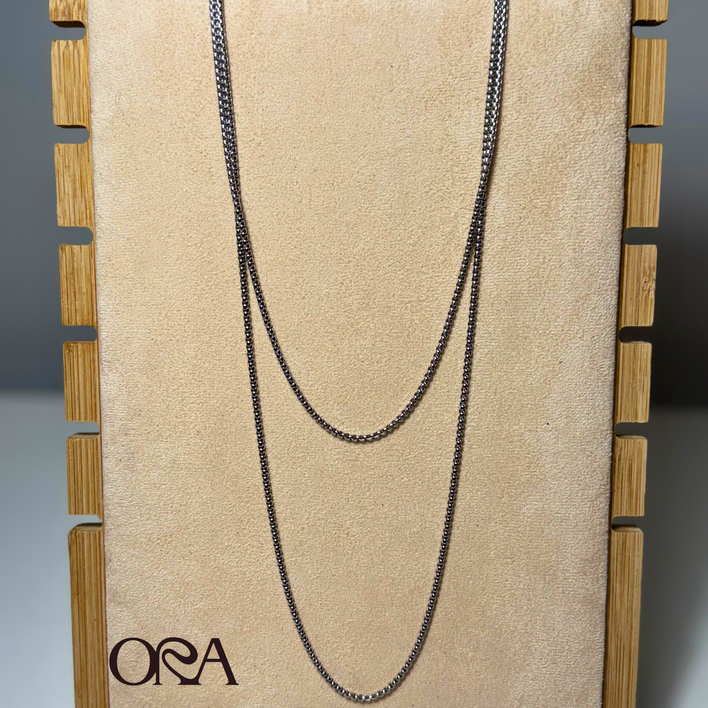 Black chain necklace on a beige card with 'ORA' branding