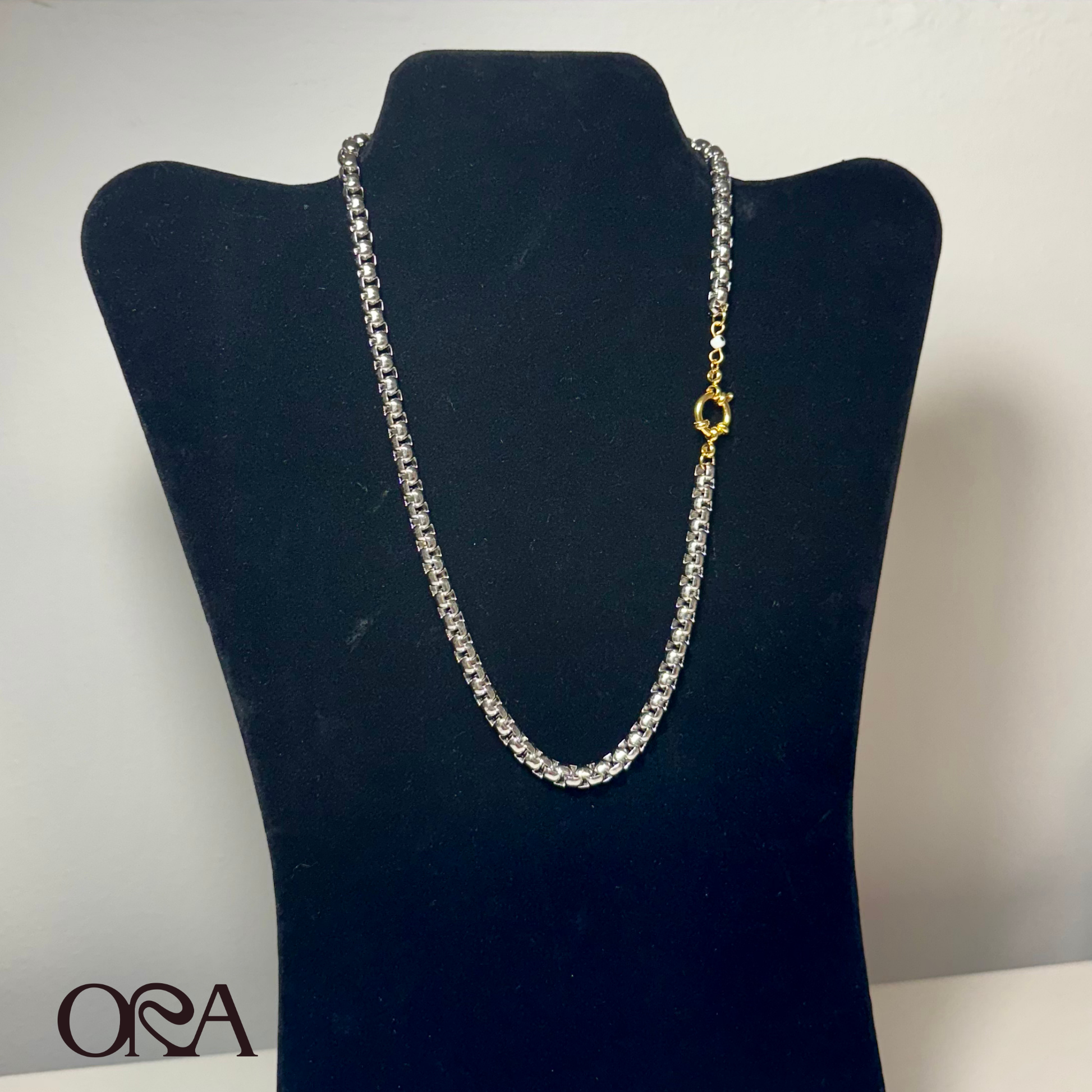 Silver chain necklace on a black velvet stand with a blurred background